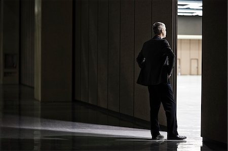 simsearch:6118-09174347,k - Businessman standing in a doorway between rooms in a convention centre arena. Fotografie stock - Premium Royalty-Free, Codice: 6118-09174255