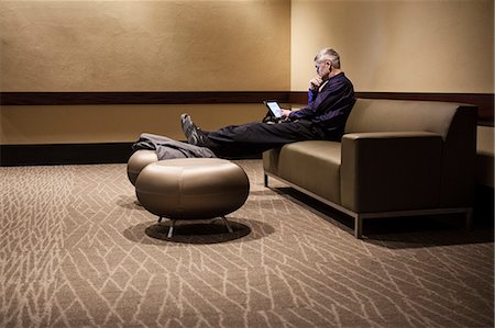 simsearch:6118-09173924,k - Mature businessman with his feet up, resting in an armchair, looking at his mobile phone. Stockbilder - Premium RF Lizenzfrei, Bildnummer: 6118-09174256