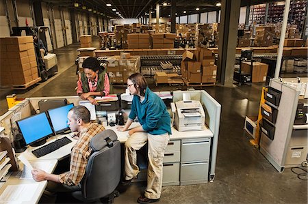 simsearch:6118-09174228,k - Three mixed race warehouse workers studying a document on a computer at the front desk of a distribution warehouse. Fotografie stock - Premium Royalty-Free, Codice: 6118-09174216