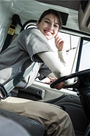 storeroom - Portrait of a uniformed Caucasian female truck driver at the wheel of her truck at a distribution warehouse. Stock Photo - Premium Royalty-Free, Code: 6118-09174232