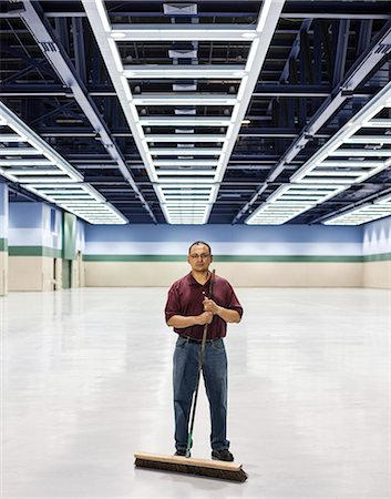 An Hispanic man standing with a broom in a large convention cener space. Foto de stock - Sin royalties Premium, Código: 6118-09174346