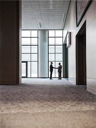 simsearch:6118-09173924,k - Two businessmen silhouetted and shaking hands in front of a large convention centre window. Stockbilder - Premium RF Lizenzfrei, Bildnummer: 6118-09174352