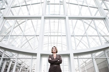 simsearch:6118-09173926,k - A portrait looking up at a Caucasian businesswoman standing next to a large graphic pattern on a window in a convention centre Stock Photo - Premium Royalty-Free, Code: 6118-09174354