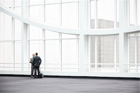 simsearch:6118-09174347,k - Two businessmen standing in a glassed in lobby area of a convention centre. Fotografie stock - Premium Royalty-Free, Codice: 6118-09174367