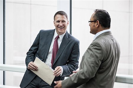 simsearch:6118-09129966,k - Two businessmen standing chatting in an open area of an office building. Stock Photo - Premium Royalty-Free, Code: 6118-09174364