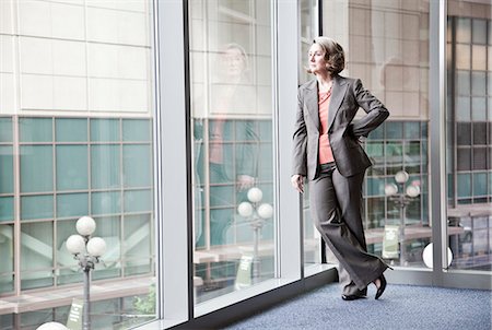 simsearch:6118-09174347,k - A Caucasian businesswoman standing next to a large window in a convention centre lobby. Fotografie stock - Premium Royalty-Free, Codice: 6118-09174369