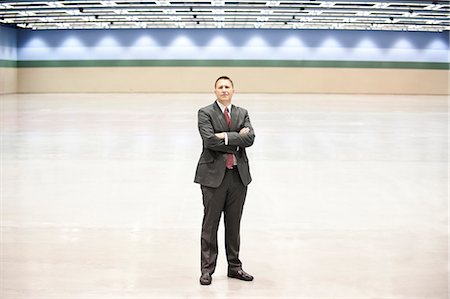 simsearch:6118-09174347,k - A portrait of a Caucasian businessman standing in the middle of a convention centre arena. Fotografie stock - Premium Royalty-Free, Codice: 6118-09174375