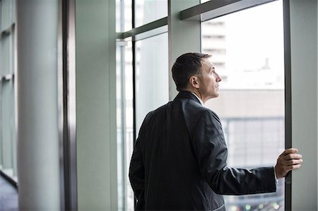 simsearch:6118-09173924,k - A Caucasian businessman standing next to and looking out of a large window in a convention centre. Stockbilder - Premium RF Lizenzfrei, Bildnummer: 6118-09174379