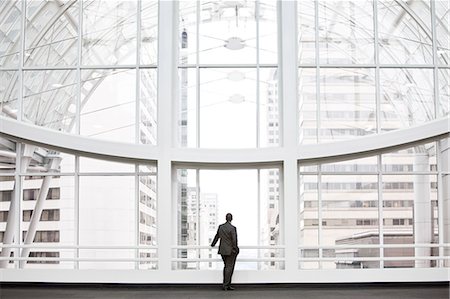 simsearch:6118-09174347,k - A businessman in silhouette standing at a large window in a convention centre lobby. Fotografie stock - Premium Royalty-Free, Codice: 6118-09174388