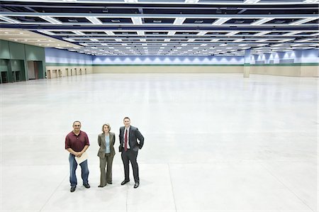simsearch:6118-09174347,k - Three business meeting planners standing in the middle of a convention centre arena. Fotografie stock - Premium Royalty-Free, Codice: 6118-09174399
