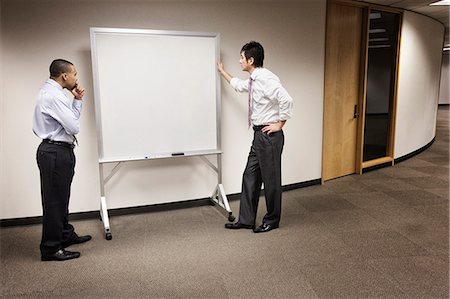simsearch:400-04850746,k - A black businessman and an Asian businessman ponder the issue of an empty white board. Photographie de stock - Premium Libres de Droits, Code: 6118-09174311