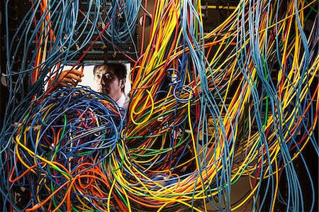 simsearch:400-07167932,k - Asian male technician working on a tangled mess of CAT 5 cables in a server room. Foto de stock - Sin royalties Premium, Código: 6118-09174315