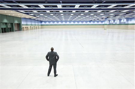 simsearch:6118-09174347,k - A view looking down on a single businessman surveying the interior of a convention centre arena. Fotografie stock - Premium Royalty-Free, Codice: 6118-09174400