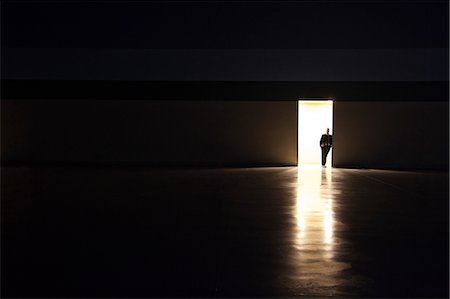 simsearch:6118-09174347,k - A man in silhouette standing in the doorway of a large convention centre arena. Fotografie stock - Premium Royalty-Free, Codice: 6118-09174404