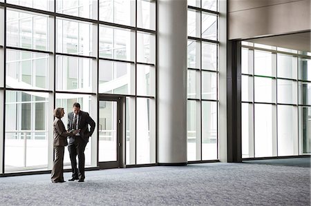 simsearch:6118-09173926,k - A Caucasian businesswoman and man in an informal meeting in front of a large window in a convention centre lobby. Stock Photo - Premium Royalty-Free, Code: 6118-09174412