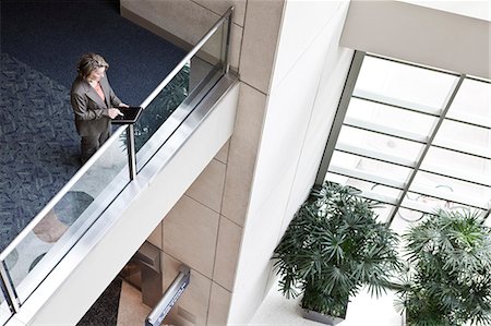 simsearch:6118-09129521,k - A view looking down on a businesswoman using a notebook computer while standing in the lobby of a convention centre. Stock Photo - Premium Royalty-Free, Code: 6118-09174415