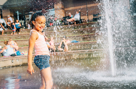 Smiling girl playing in public fountain in summer Stock Photo - Premium Royalty-Free, Code: 6118-09183247