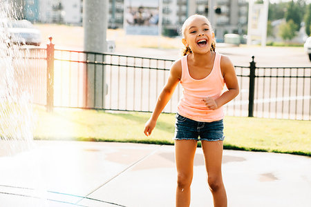 Smiling girl playing in public fountain in summer Stock Photo - Premium Royalty-Free, Code: 6118-09183246