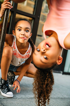 faire des grimaces - Happy, smiling girls hanging from bike rack bar on sidewalk Photographie de stock - Premium Libres de Droits, Code: 6118-09183260