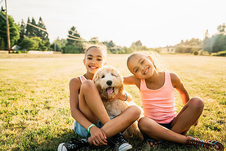 puppy people not humour not group not kitten - Portrait of smiling happy girls hugging labradoodle puppy in park Stock Photo - Premium Royalty-Free, Code: 6118-09183266