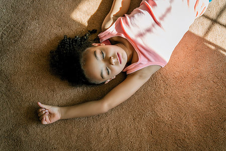 Girl laying on living room carpet in the sunlight Stock Photo - Premium Royalty-Free, Code: 6118-09183222