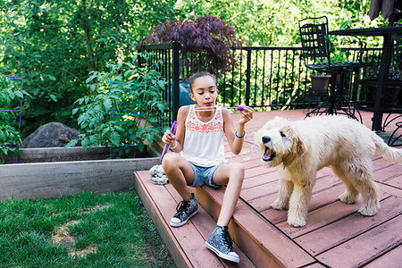 simsearch:6118-09018684,k - Tween Girl Blowing Bubbles with Labradoodle Puppy in Backyard Foto de stock - Sin royalties Premium, Código: 6118-09183234