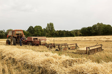 simsearch:649-06353290,k - Tractor and straw baler in wheat field, farmer baling straw. Fotografie stock - Premium Royalty-Free, Codice: 6118-09183452