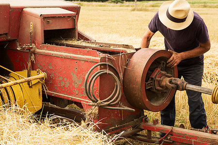 farmer with hat tractor and field - Tractor and straw baler in wheat field, farmer checking equipment. Stock Photo - Premium Royalty-Free, Code: 6118-09183454