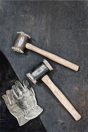 High angle close up of two hammers and pair of leather safety gloves in a metal workshop. Foto de stock - Sin royalties Premium, Código: 6118-09112013