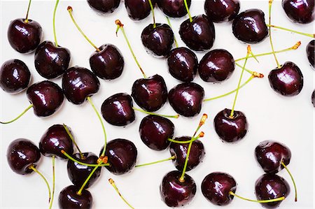 plain background - High angle close up of ripe red cherries spread out on a worktop. Stock Photo - Premium Royalty-Free, Code: 6118-09112117