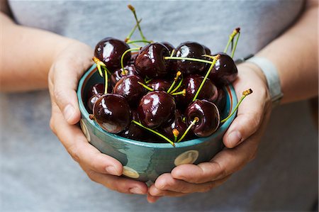 simsearch:6118-08947561,k - A woman's hands holding a bowl of ripe dark red cherries. Foto de stock - Royalty Free Premium, Número: 6118-09112116