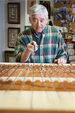 senior pattern - Asian American senior male checking the balance on a 5 weight fly fishing rod for sale in a fly fishing shop. Stock Photo - Premium Royalty-Free, Code: 6118-09129459