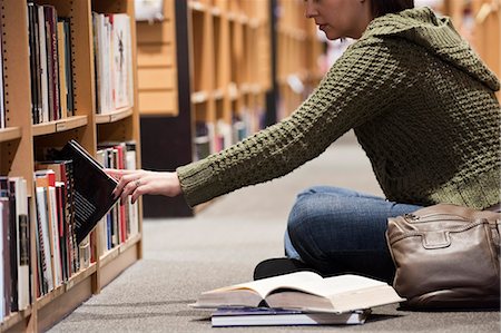 simsearch:6118-07354058,k - Caucasian female browsing through books in a bookstore, while sitting on the floor in front of a rack of books. Stock Photo - Premium Royalty-Free, Code: 6118-09129477