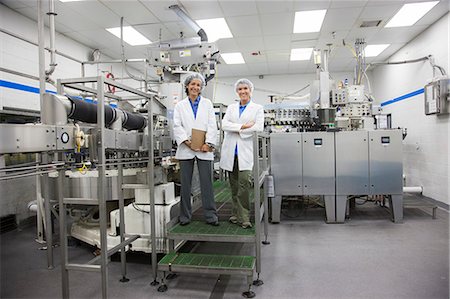 simsearch:6118-09129432,k - A portrait of two female technicians in the bottling area of a bottled water plant. Fotografie stock - Premium Royalty-Free, Codice: 6118-09129413