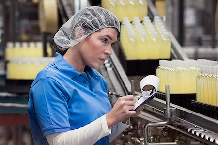 A Caucasian female employee wearing a head net and working on a production line in a bottling plant. Stock Photo - Premium Royalty-Free, Code: 6118-09129427