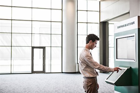 simsearch:6118-07351305,k - Businessman at an information kiosk in a large lobby area. Stock Photo - Premium Royalty-Free, Code: 6118-09129550