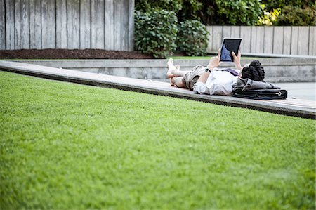 Businessman in a downtown city park taking a break and checking his computer notebook Stock Photo - Premium Royalty-Free, Code: 6118-09129575