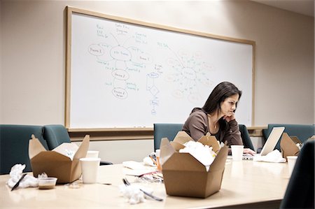 Caucasian woman working through lunch at a conference room table. Photographie de stock - Premium Libres de Droits, Code: 6118-09129500