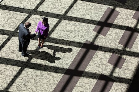 simsearch:6118-09129521,k - Black businessman and woman meeting in the lobby of a large business centre. Stock Photo - Premium Royalty-Free, Code: 6118-09129649