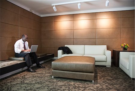 Black businessman working on a lap top in a hotel lobby. Stock Photo - Premium Royalty-Free, Code: 6118-09129611