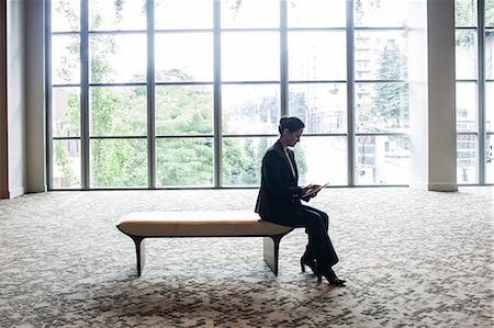 simsearch:6118-07351305,k - Caucasian businesswoman working on a computer while sitting on a bench in a business centre lobby. Stock Photo - Premium Royalty-Free, Code: 6118-09129635