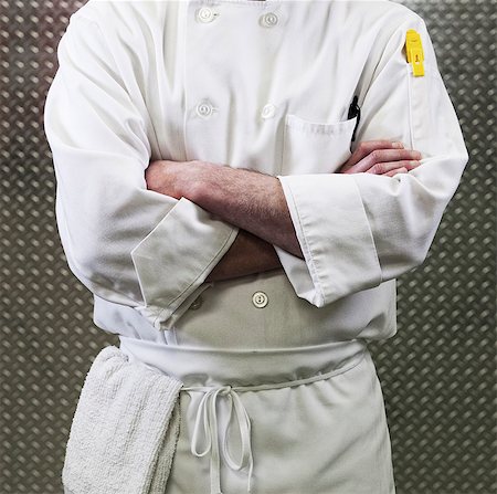 Chef in a white jacket and apron around his waist with arms folded. Mid section. Stock Photo - Premium Royalty-Free, Code: 6118-09129753