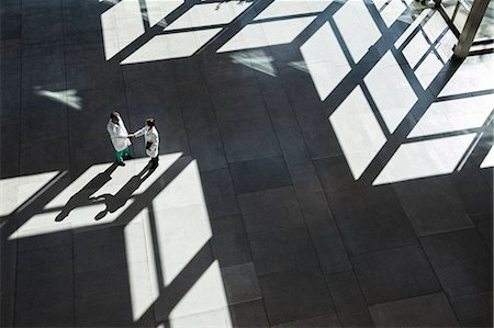 person on scale doctor - Man and woman doctors conferring over medical records in a hospital lobby. Stock Photo - Premium Royalty-Free, Code: 6118-09129714