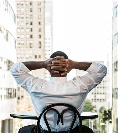 simsearch:6118-09144821,k - Black business man sitting at a lobby table looking at the cityscape through a large window. Photographie de stock - Premium Libres de Droits, Code: 6118-09129735