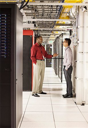 simsearch:6118-09129858,k - Computer technicians discussion an issue in a large computer server farm. Foto de stock - Sin royalties Premium, Código: 6118-09129817