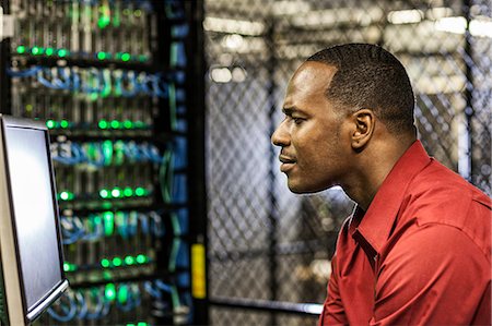 simsearch:6118-09129858,k - Black man technician doing diagnostic tests  on computer servers in server farm. Foto de stock - Sin royalties Premium, Código: 6118-09129816