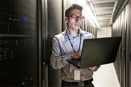 Hispanic man technician doing diagnostic tests on computer servers in a large server farm. Stock Photo - Premium Royalty-Free, Code: 6118-09129837