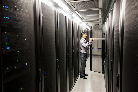 Hispanic man technician doing diagnostic tests on computer servers in a large server farm. Stock Photo - Premium Royalty-Free, Code: 6118-09129834