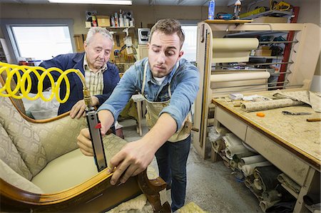 Young Caucasian man learning the art of upholstery from a senior male upholsterer. Stock Photo - Premium Royalty-Free, Code: 6118-09130080