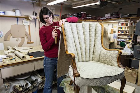 simsearch:845-05837814,k - A young female upholsterer using a tack hammer on a chair in an upholstery shop. Foto de stock - Royalty Free Premium, Número: 6118-09130082